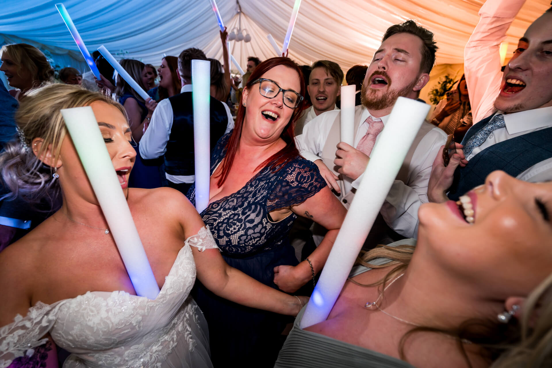 Joyful wedding guests dancing with light sticks