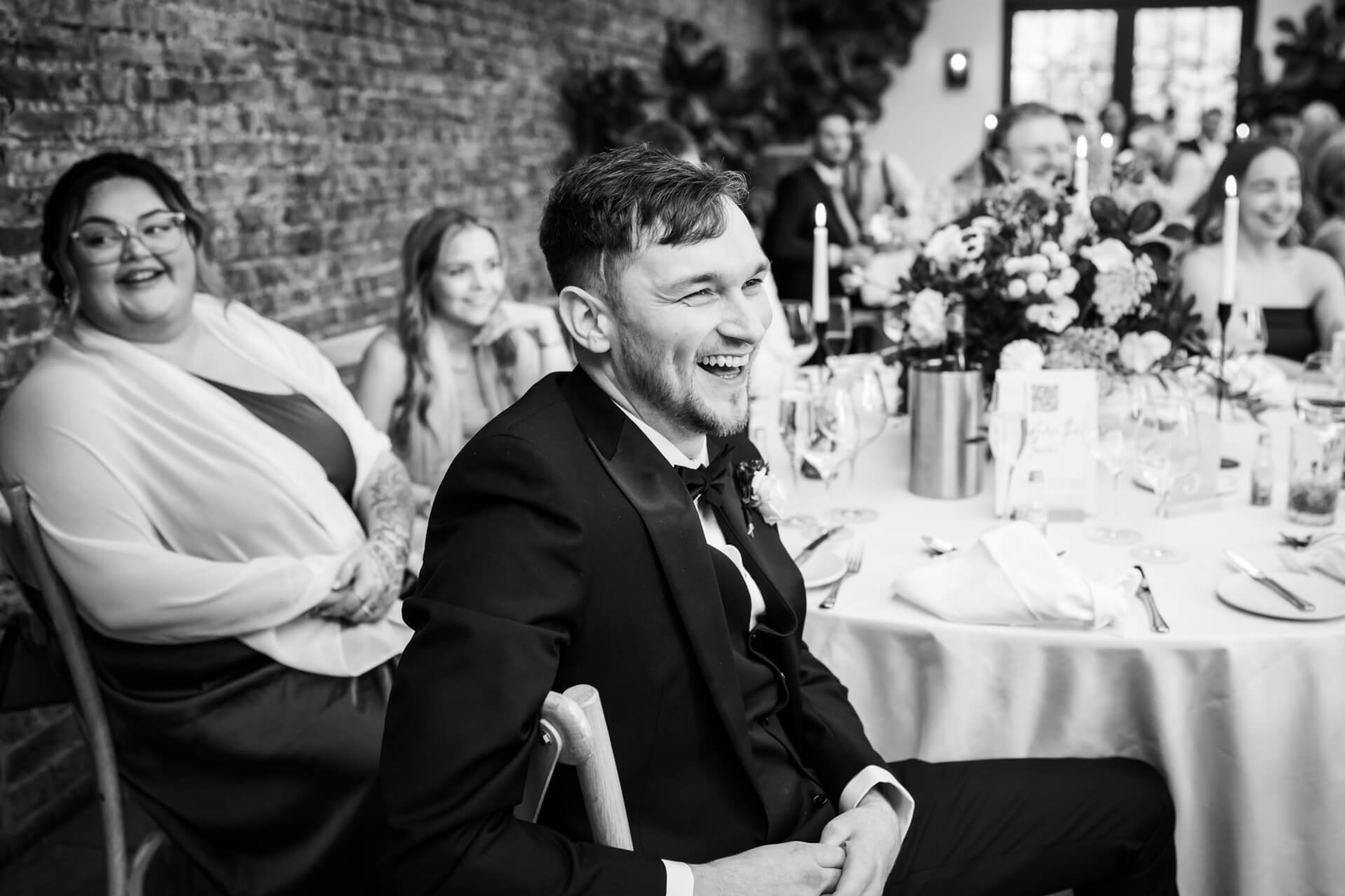 Laughing guests at a wedding reception table.