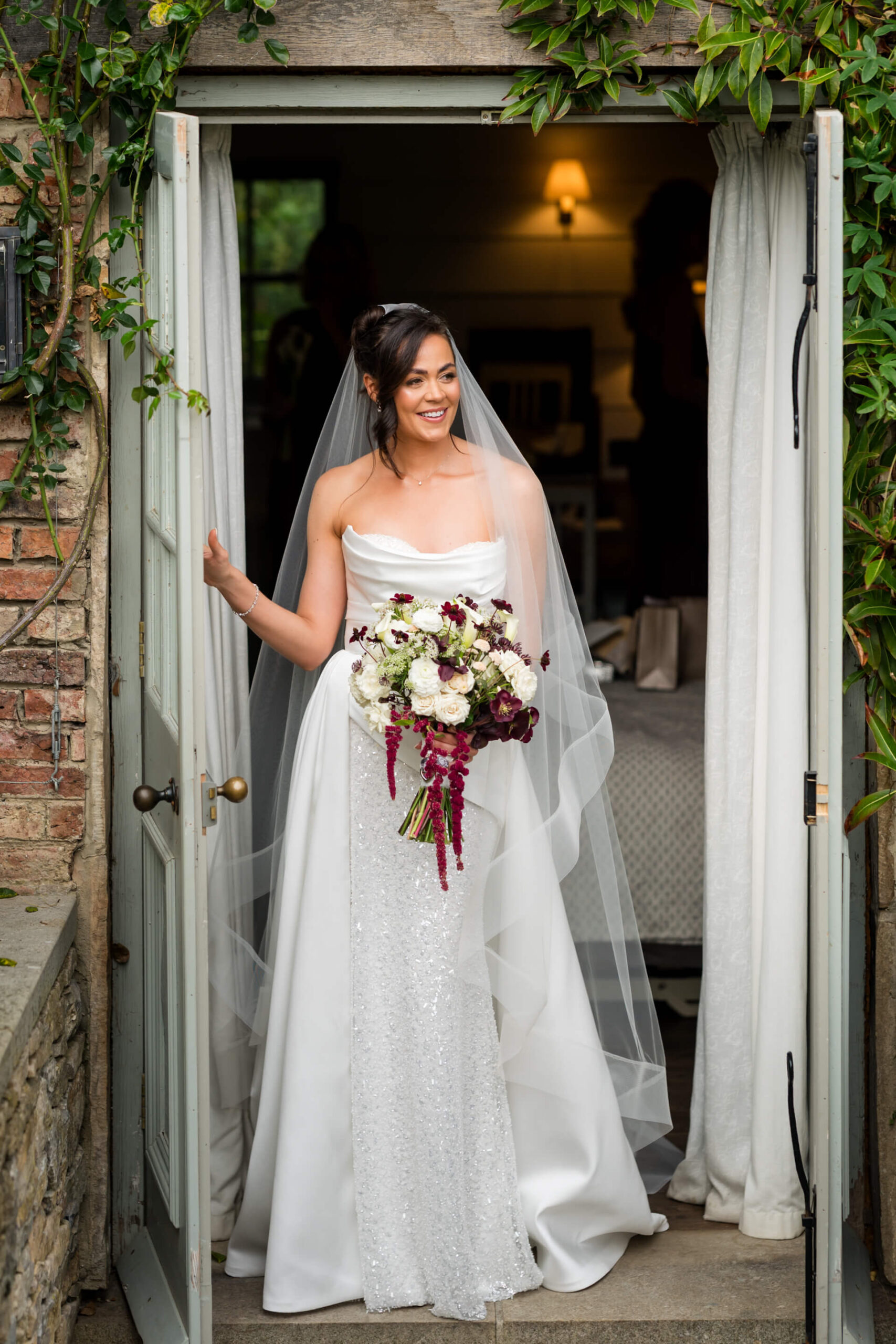 Bride smiling in white dress with bouquet.
