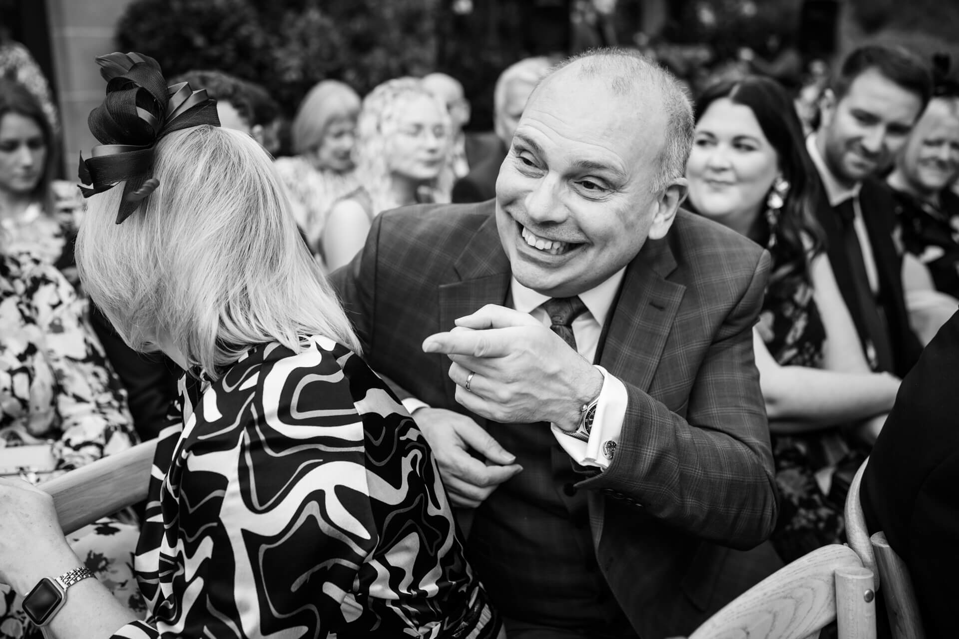 Smiling man at outdoor gathering chatting animatedly.